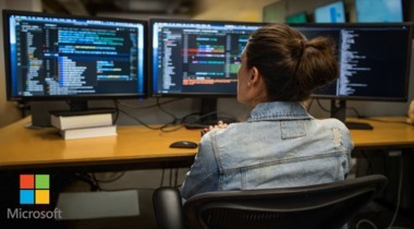 Mujer sentada frente a varias pantallas de computador