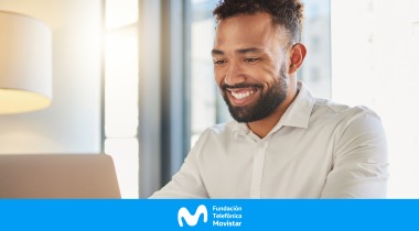 Hombre sonriendo mientras mira la pantalla de un computador