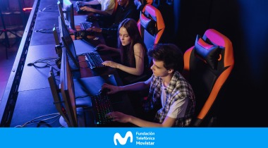 Jóvenes frente a pantallas de computador, en una sala de videojuegos con luces de colores