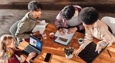 Grupo de cuatro personas reunidas alrededor de una mesa en medio de una reunión laboral