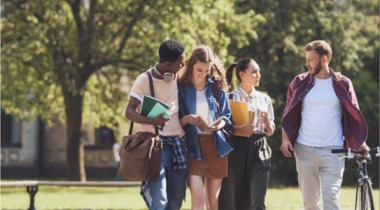 Grupo de jóvenes conversando en un campus universitario, asociado al aprendizaje de inglés para tecnología